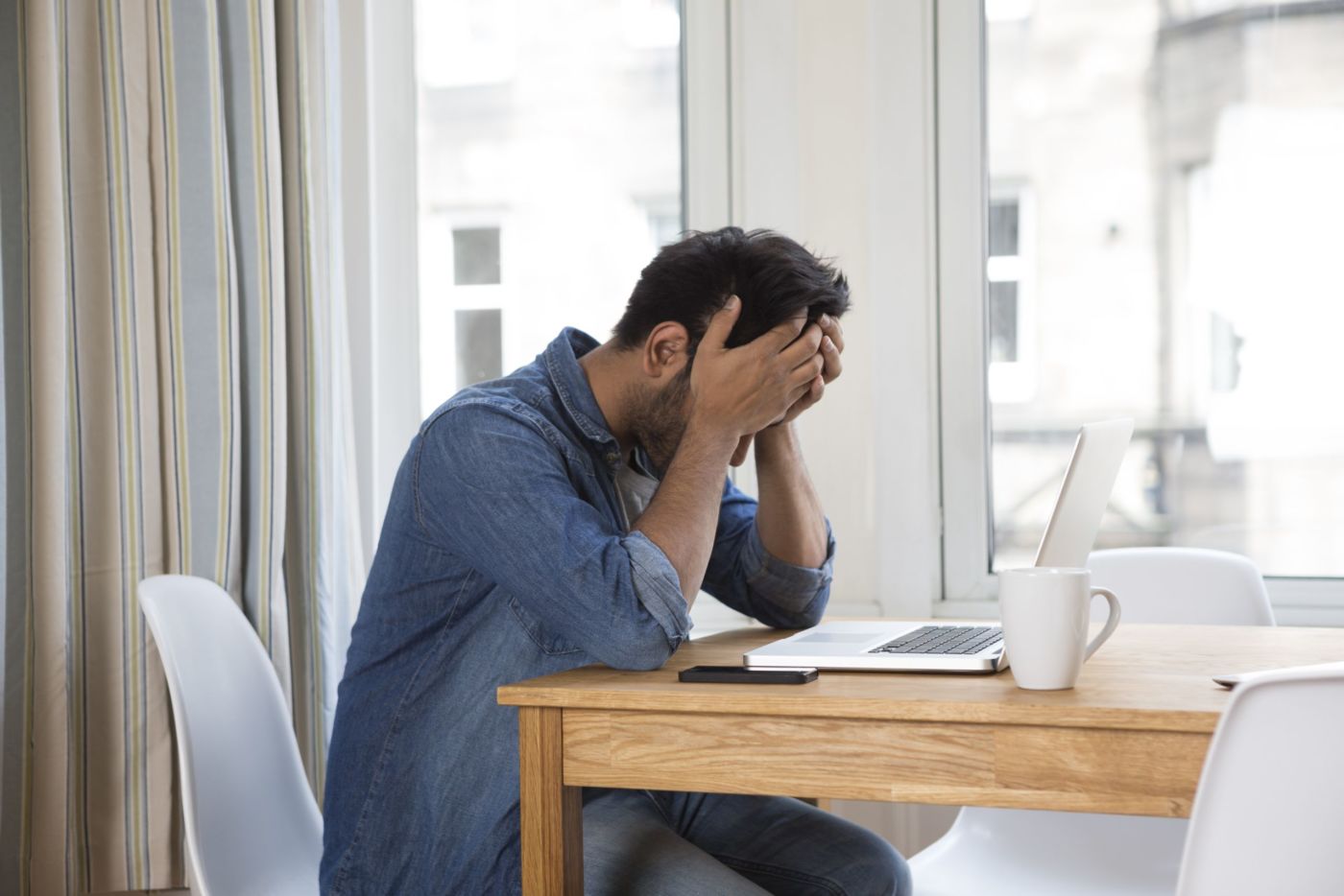 Man sitting at a table with his head in his hands.